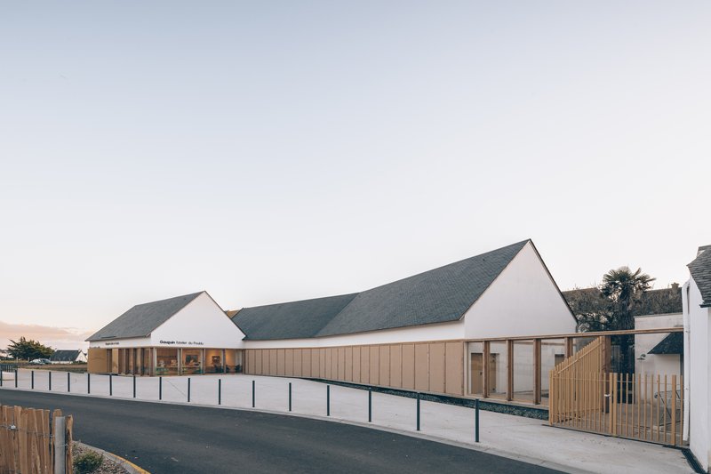 View of the gabled roofline and timber cladding along the entry drive at twilight