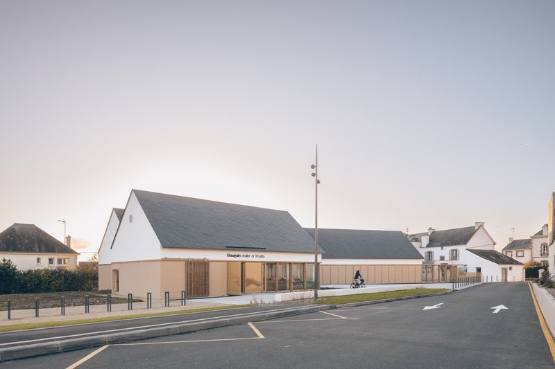Street view of the gabled slate roof building with timber cladding and glazed entrance at dusk
