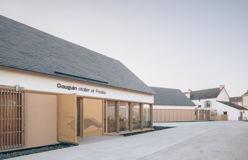 Facade detail showing the vertical timber screen beside the glazed entrance and grey slate roof