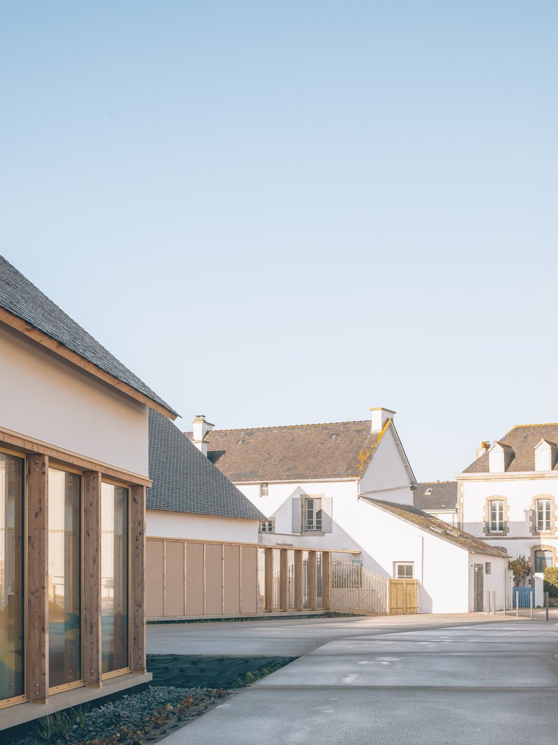 Courtyard view showing gabled volumes with dark slate roofs and timber-clad facades against a clear sky
