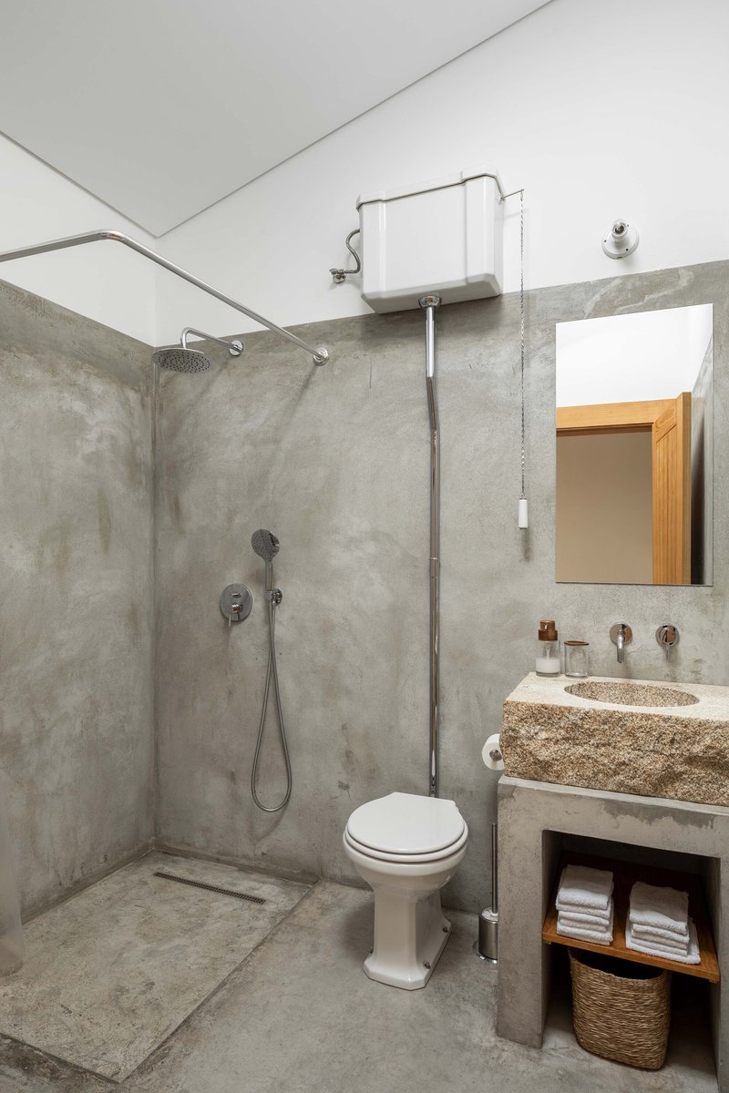 Bathroom with concrete walls, open shower area, and aggregate stone countertop with undermount sink