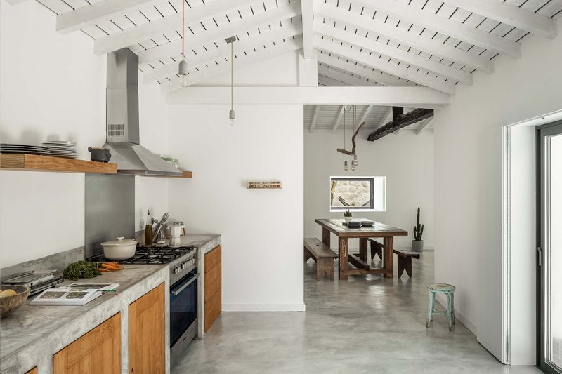 Open kitchen with timber cabinetry and concrete countertop looking through to the adjacent dining space