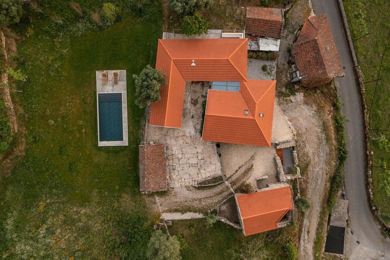 Aerial view of the terracotta tile roofs around a stone paved courtyard surrounded by trees