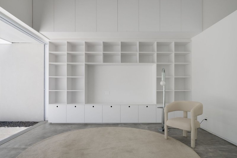 Built-in white shelving unit wrapping the corner with lower cabinets and a clerestory window above