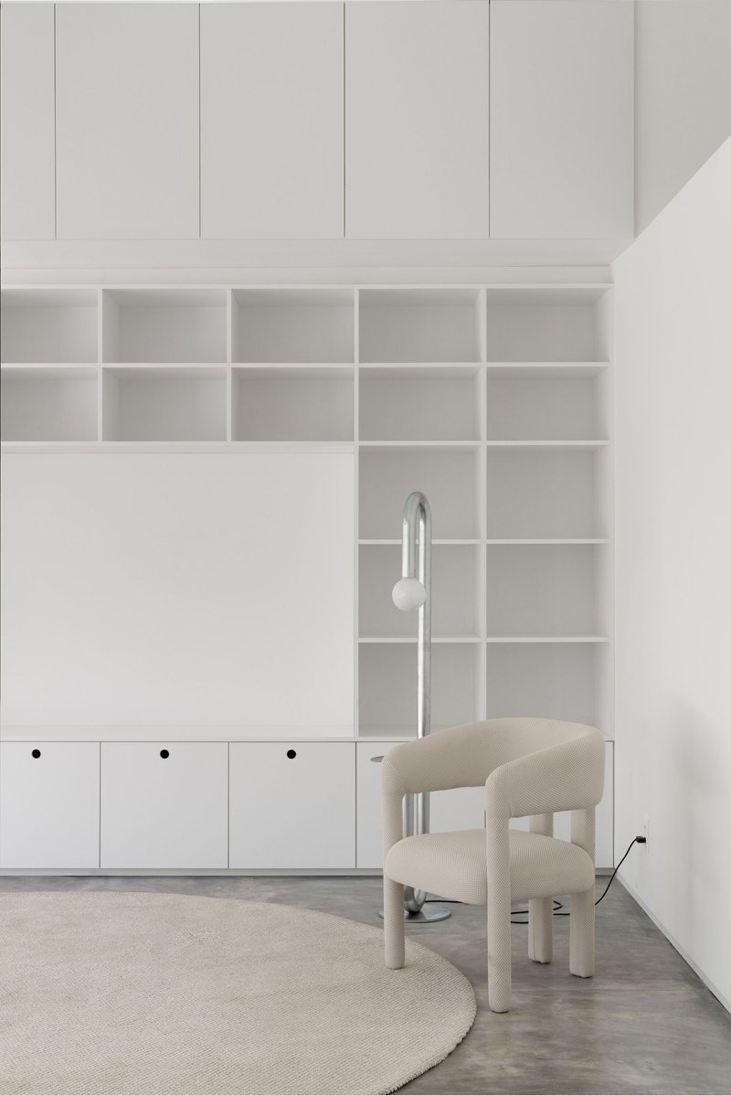 Detail of the white grid shelving with a chrome floor lamp positioned between wall and chair