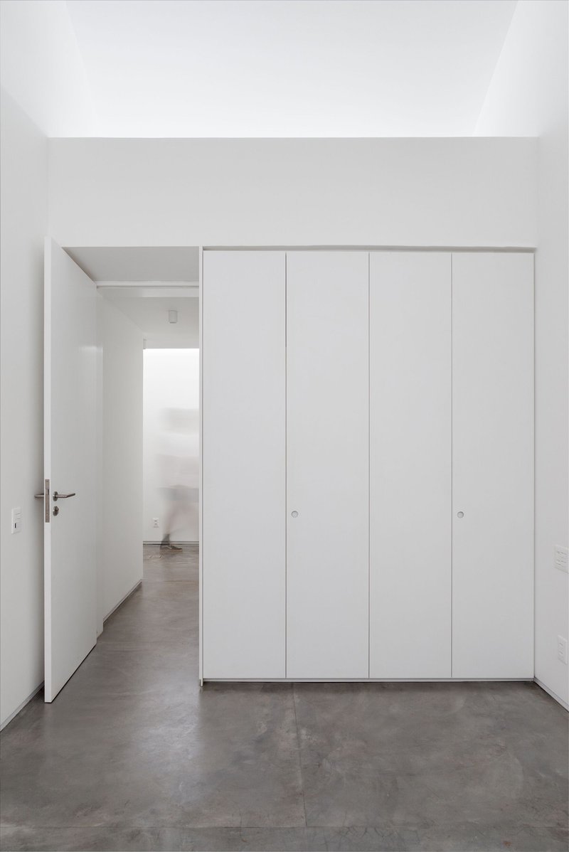 Room with floor-to-ceiling white storage doors and an open doorway revealing an adjacent space