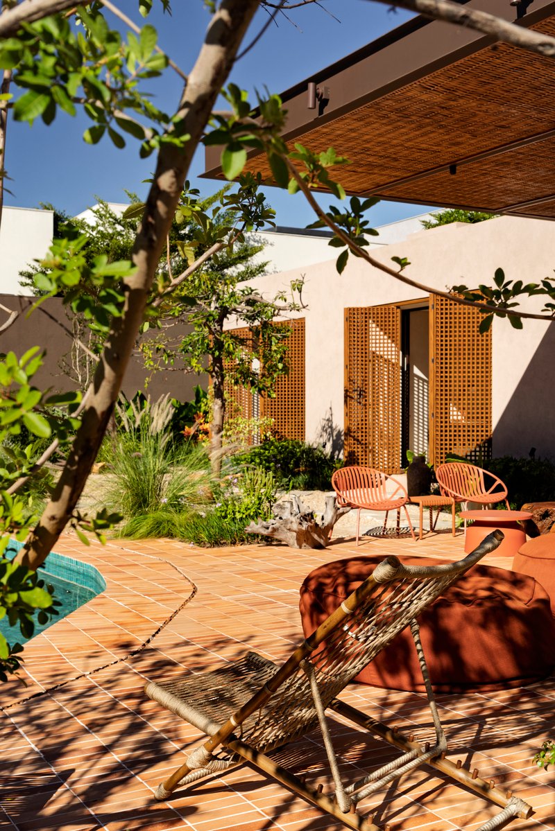 Interior courtyard with terracotta tile paving and mesh seating beneath fruit tree branches