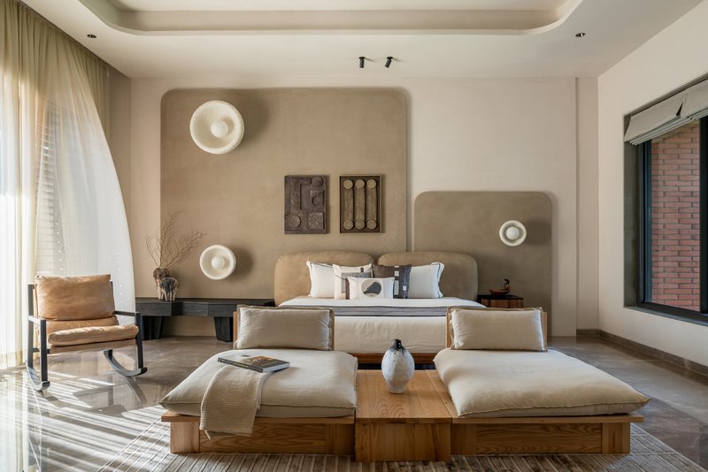 Bedroom with rounded plaster wall niches and circular sconces above upholstered headboard
