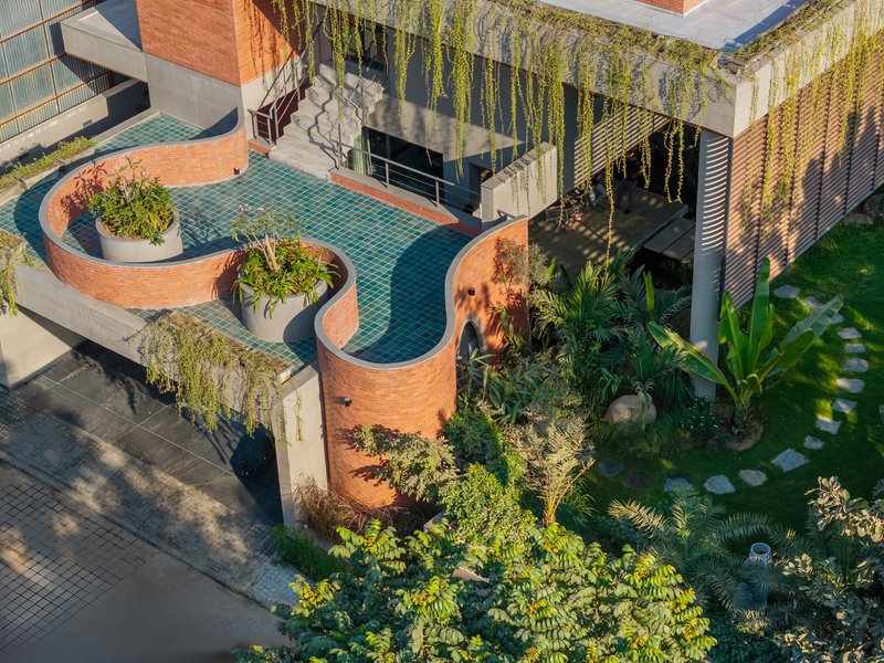 Aerial view of curved brick planters enclosing a tiled courtyard with cascading greenery and tropical plants