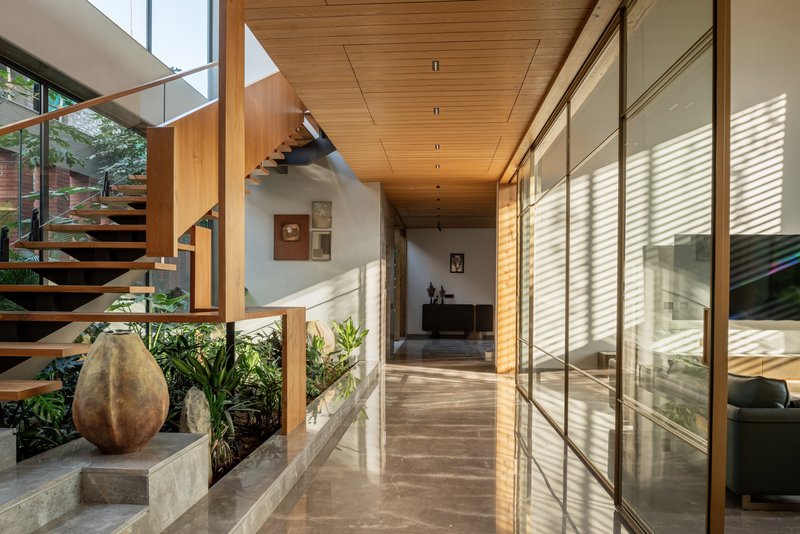 Interior corridor with timber ceiling and glass walls casting striped shadow patterns on the floor