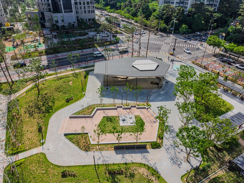 Aerial view of the canopy structure set within terraced gardens and curved pathways beside an intersection