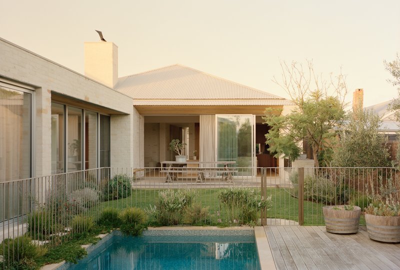 Rear terrace and pool framed by metal fencing with native grasses at dusk