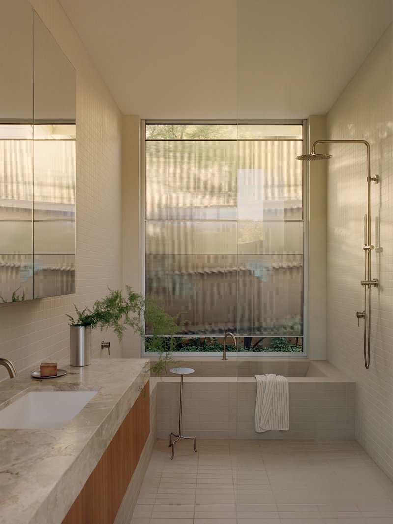Bathroom with terrazzo vanity and translucent window shades filtering afternoon light