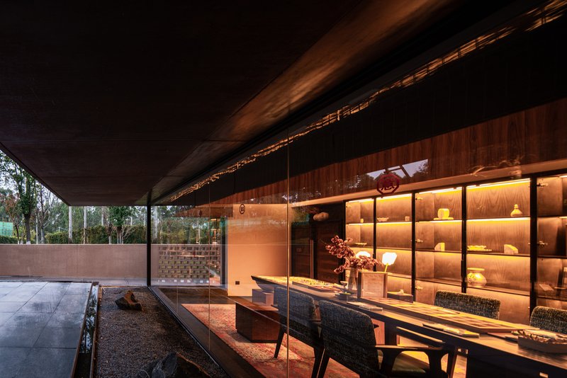 Covered terrace with exposed timber beams and illuminated display shelving beside exterior dining table