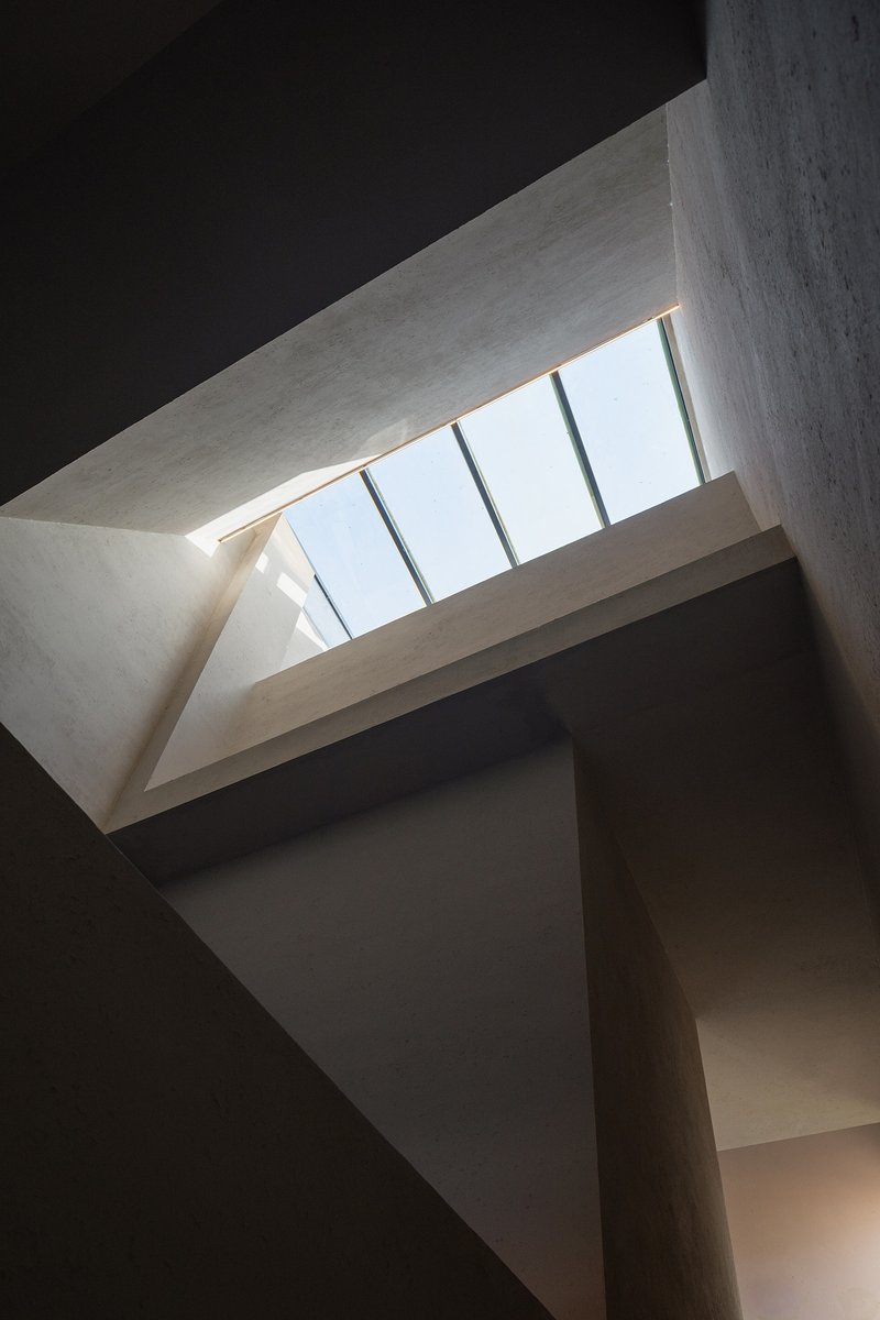 Interior skylight view showing angled concrete beams framing a row of clerestory glazing against sky
