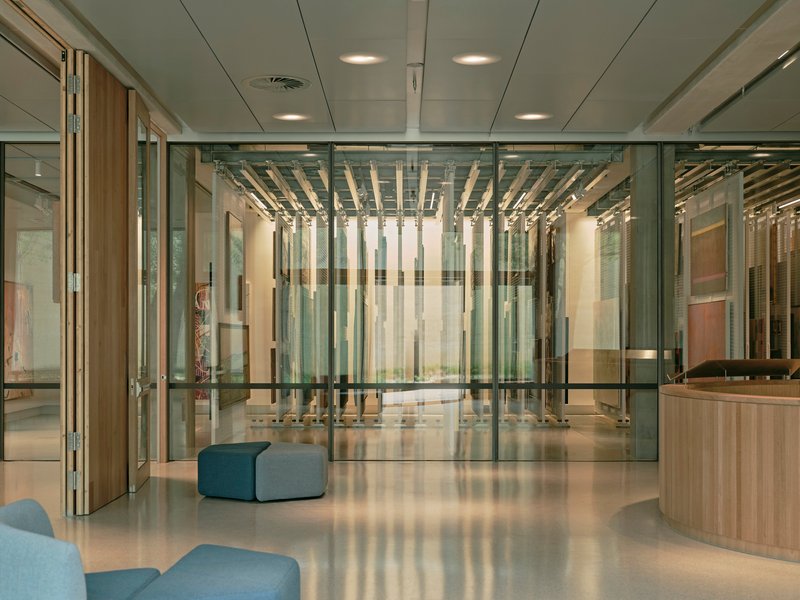 Lobby with glass partitions revealing timber baffle ceiling and polished concrete floor with blue upholstered seating