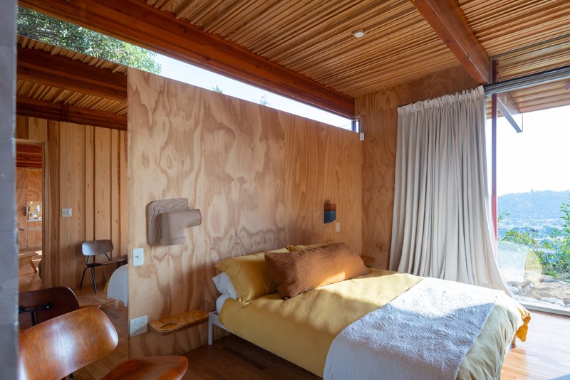 Bedroom with plywood headboard wall and clerestory window casting natural light onto the bed