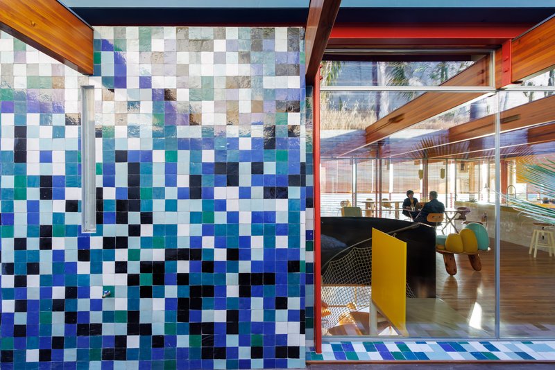 Glass wall looking into an interior space through a timber frame with pixelated tile facade