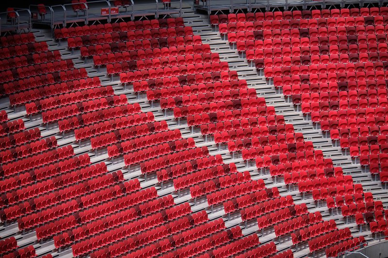 Diagonal view across stadium seating rows with red seats and grey concrete aisles