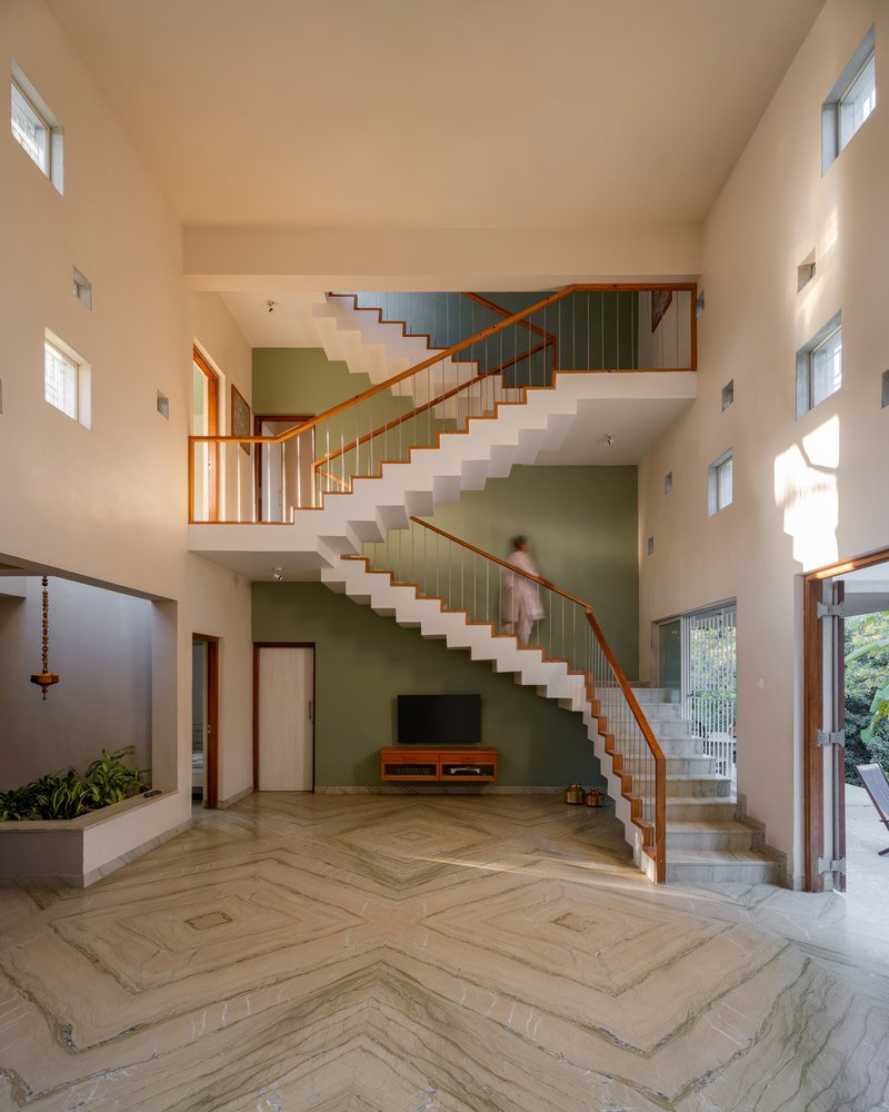 Open staircase with timber handrails ascending across a green accent wall in the main living space