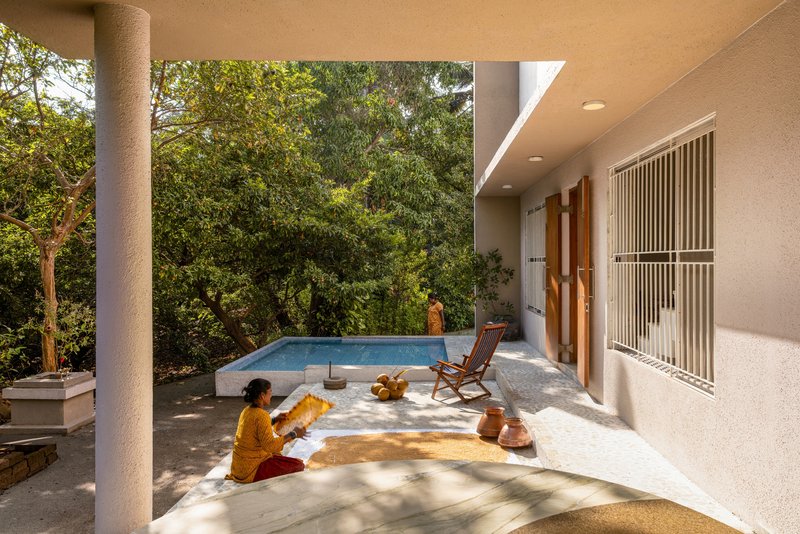 Covered terrace with circular column, raised pool edge and person seated in morning sun