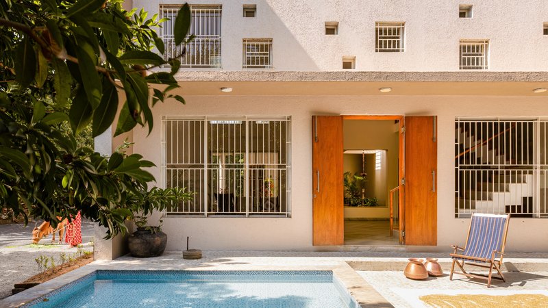 Rear facade with timber pivot doors, metal window grilles and raised pool at dusk