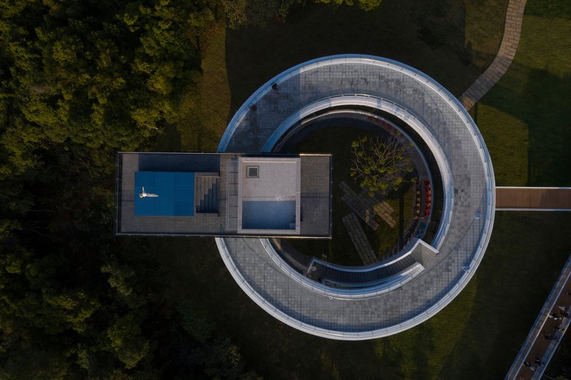 Top-down view of the double-ring structure with pool terrace and concentric tiled pathways amid green lawn