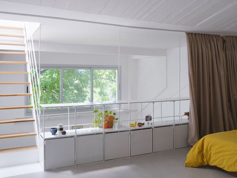 Modular storage system with grey cabinetry below a horizontal window framed by taupe curtains and exposed ceiling joists