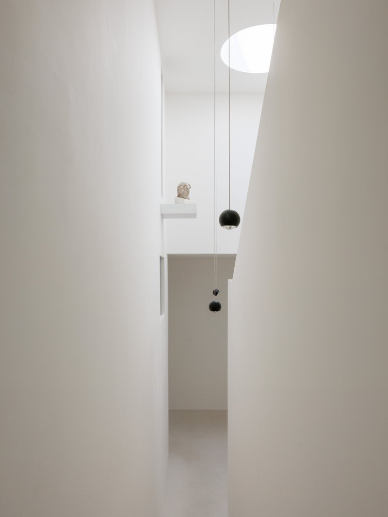 Narrow view through doorway showing pendant lights and a small sculpture on a shelf niche