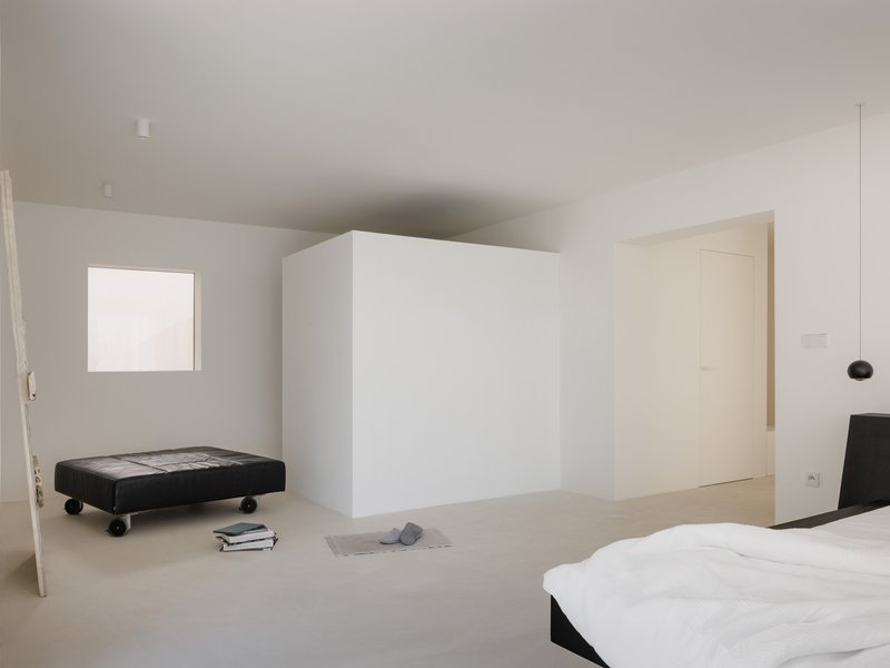 Upper floor bedroom with a freestanding white volume and a square window opening to sky