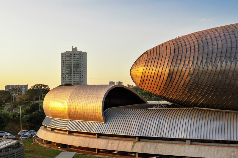 Tubular ribbed metal roof forms stacked and interlocking above a concrete base at golden hour