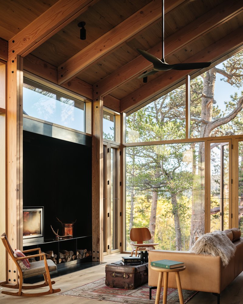 Living room with exposed timber ceiling beams and floor-to-ceiling glass overlooking autumn aspens