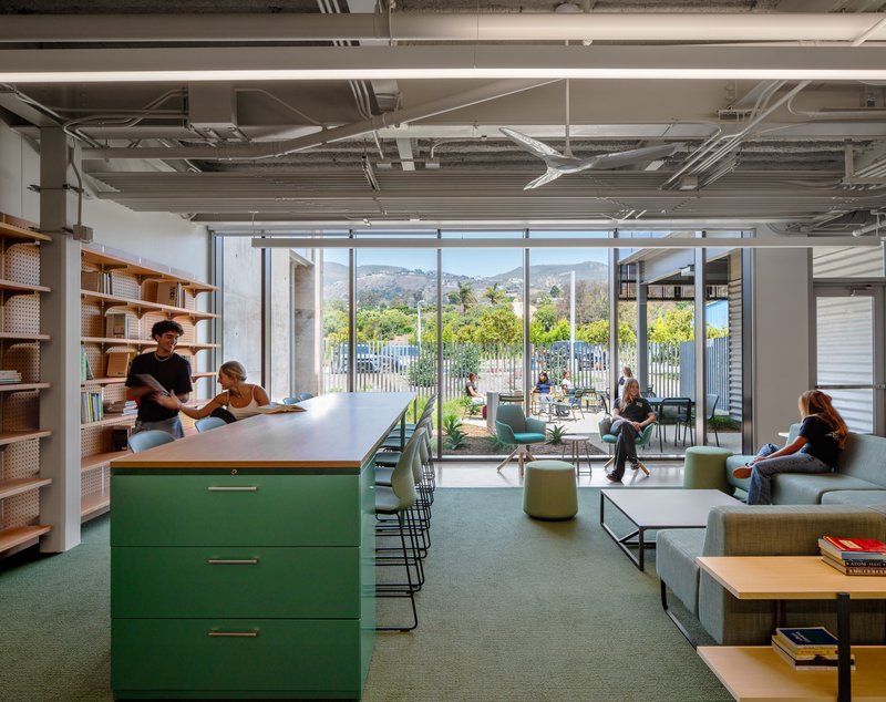 Collaborative area with green island counter, floor-to-ceiling windows overlooking hills, and students working