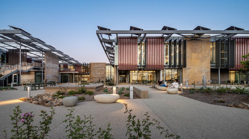 Central courtyard with gravel paths, planted beds, and timber-clad facades at twilight