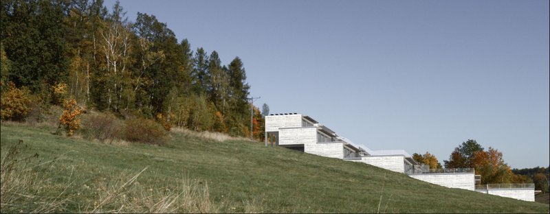 Stepped residential volumes follow the natural hillside, creating a low-impact relationship between architecture and landscape.