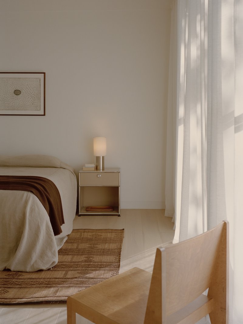 Bedroom corner with bedside table and linen curtains filtering afternoon light