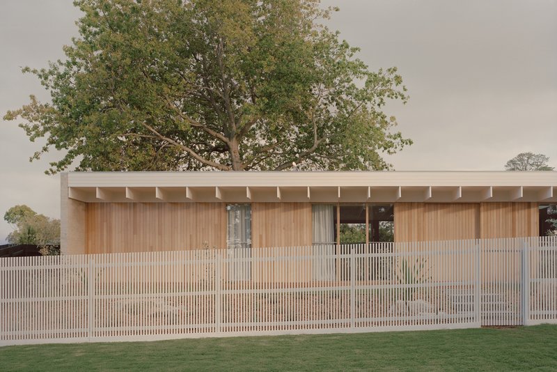 Horizontal timber slat fence screening the timber-clad facade beneath an overcast sky