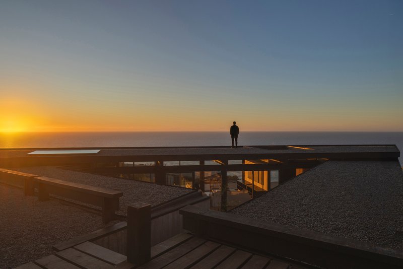 Flat roof with skylight and figure silhouetted against the ocean horizon at sunset