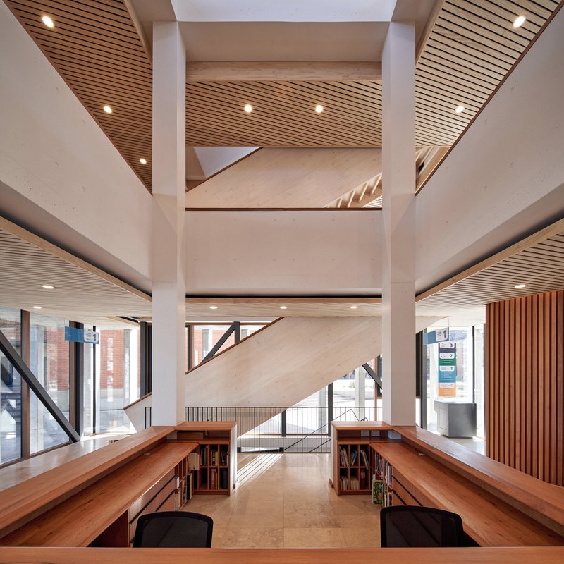 Multi-story atrium with plywood reading desks, slatted timber ceilings and concrete structural walls