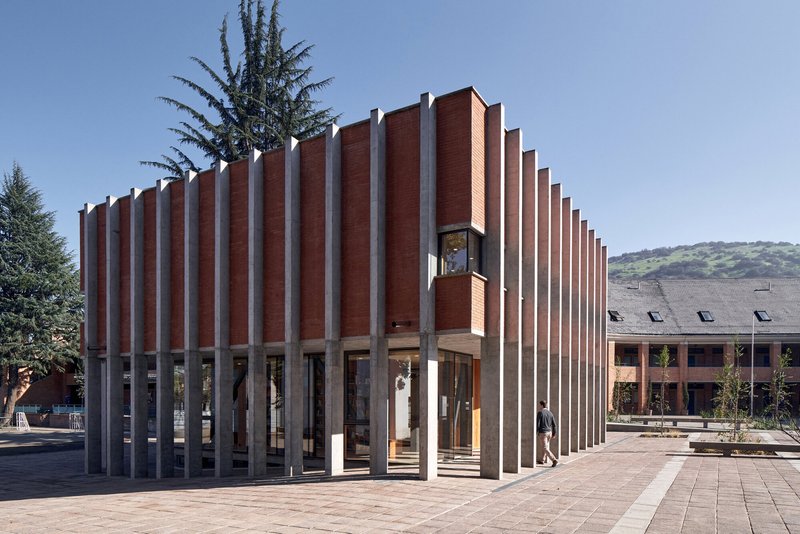 Pavilion with alternating red brick and white concrete fins on a paved plaza with surrounding trees