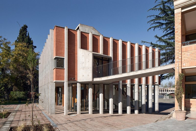Colonnade with ribbed facade panels rising above ground-level pilotis and a cantilevered upper terrace