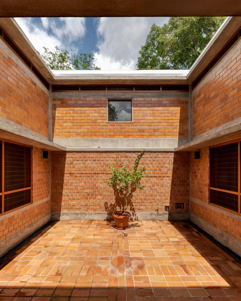 Interior courtyard with terracotta brick walls and tiled floor surrounding a potted plant under open sky