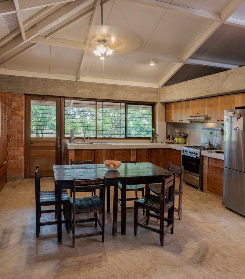 Kitchen and dining area with timber cabinetry, horizontal louvre windows, and vaulted timber ceiling