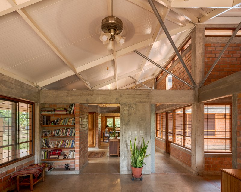 Living space with concrete structure and exposed brick walls beneath a paneled gable ceiling with pendant light