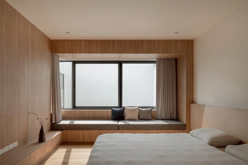 Bedroom with timber-framed window seat overlooking an overcast sky and low platform bed