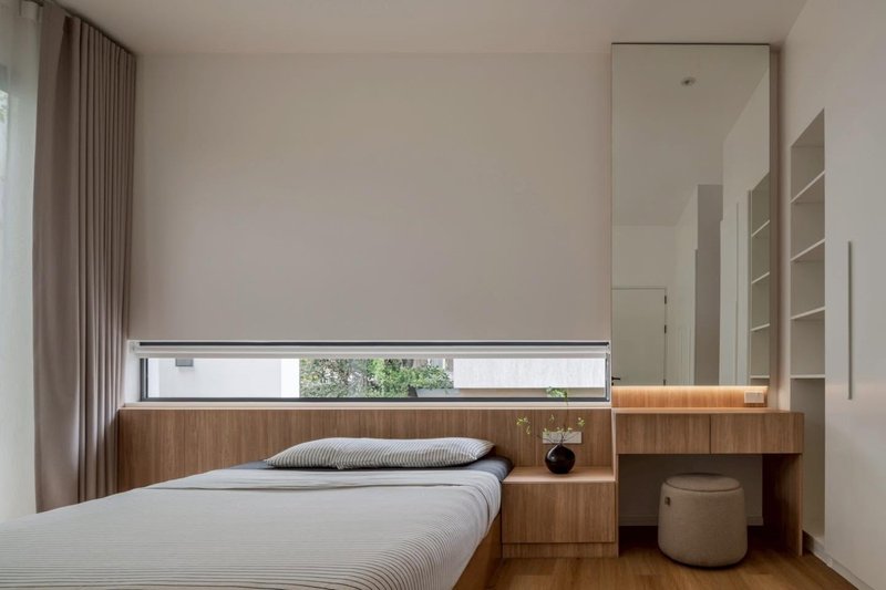 Bedroom with integrated timber bed platform and horizontal window slot framing greenery outside