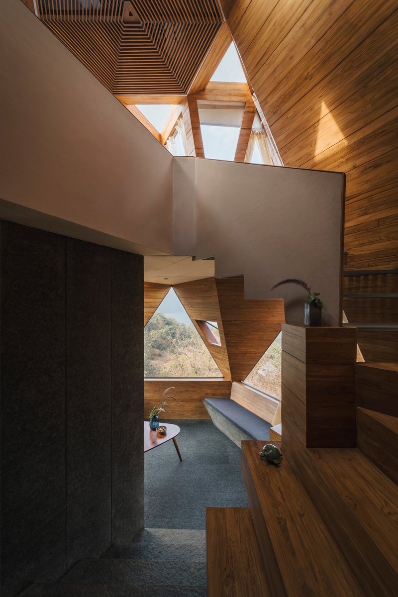 Interior view of timber-lined volume with triangular windows and floating planes under ribbed ceiling