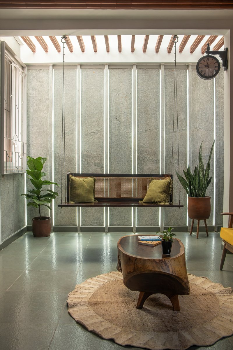 Living room with vertical backlit panels in the concrete wall and a suspended cane swing seat