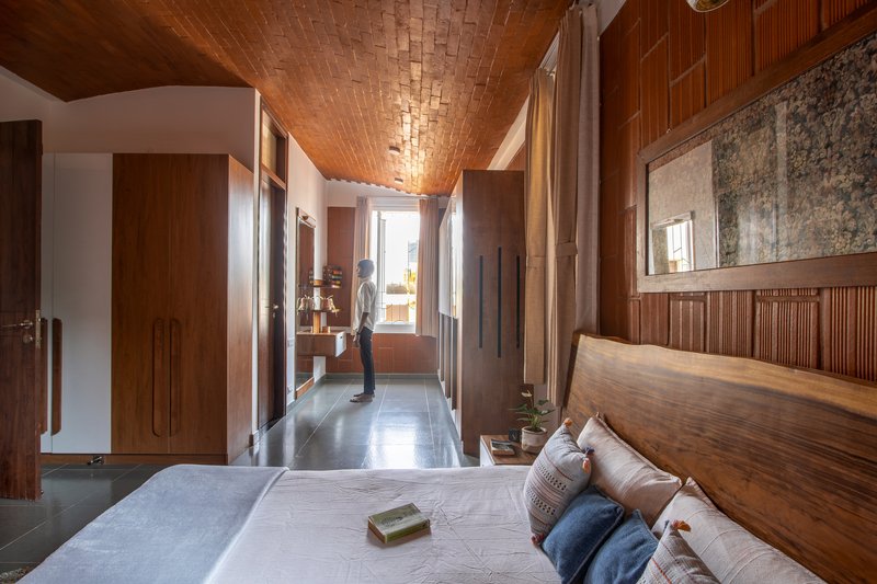 Bedroom with vaulted brick ceiling and timber paneling as a person stands in the doorway