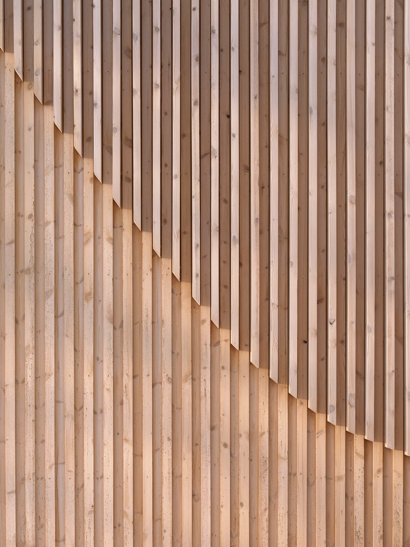 Close-up of staggered timber slat wall creating a rhythmic pattern of light and shadow